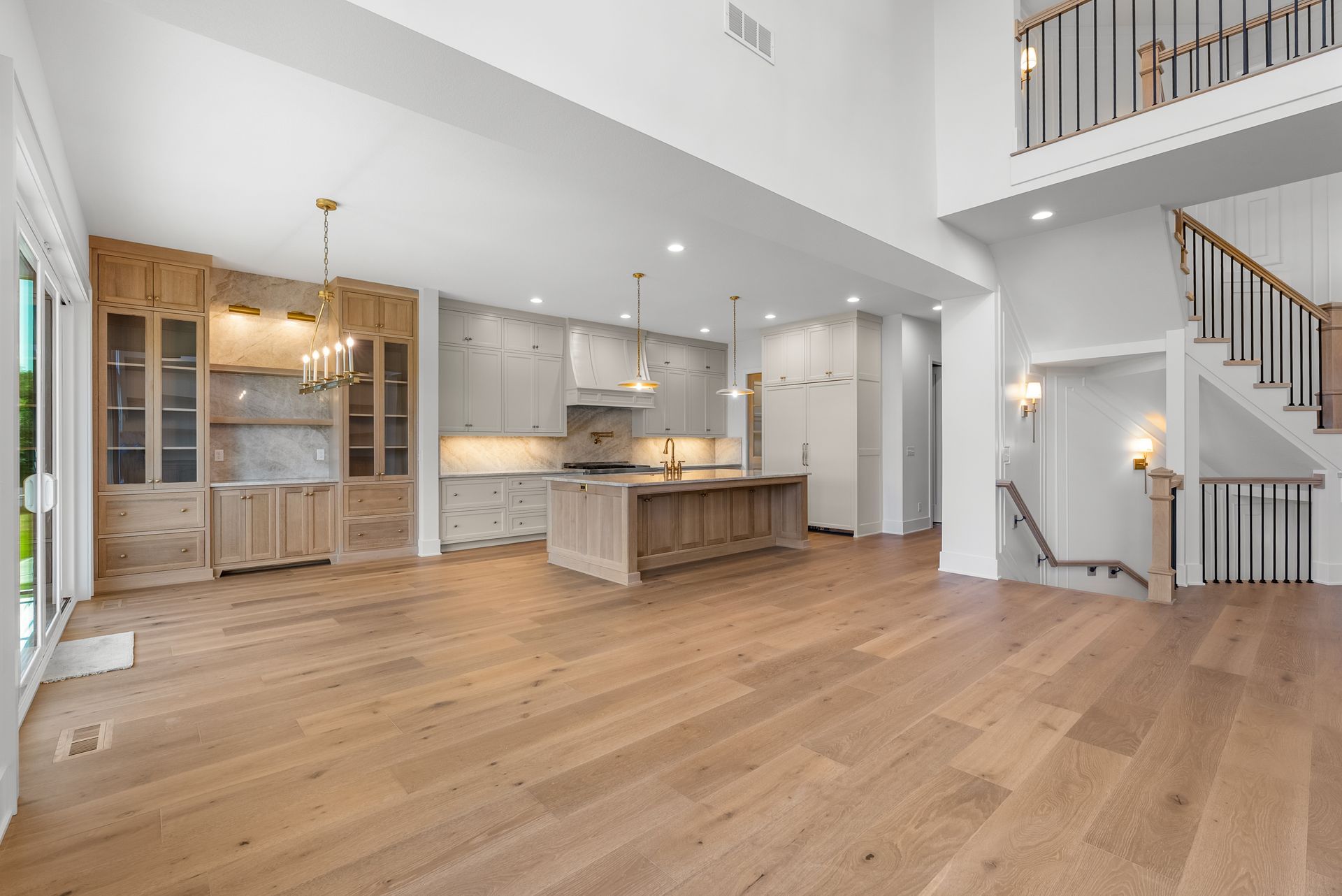 Spacious, light-filled kitchen with wood cabinets, island, and staircase to a loft.