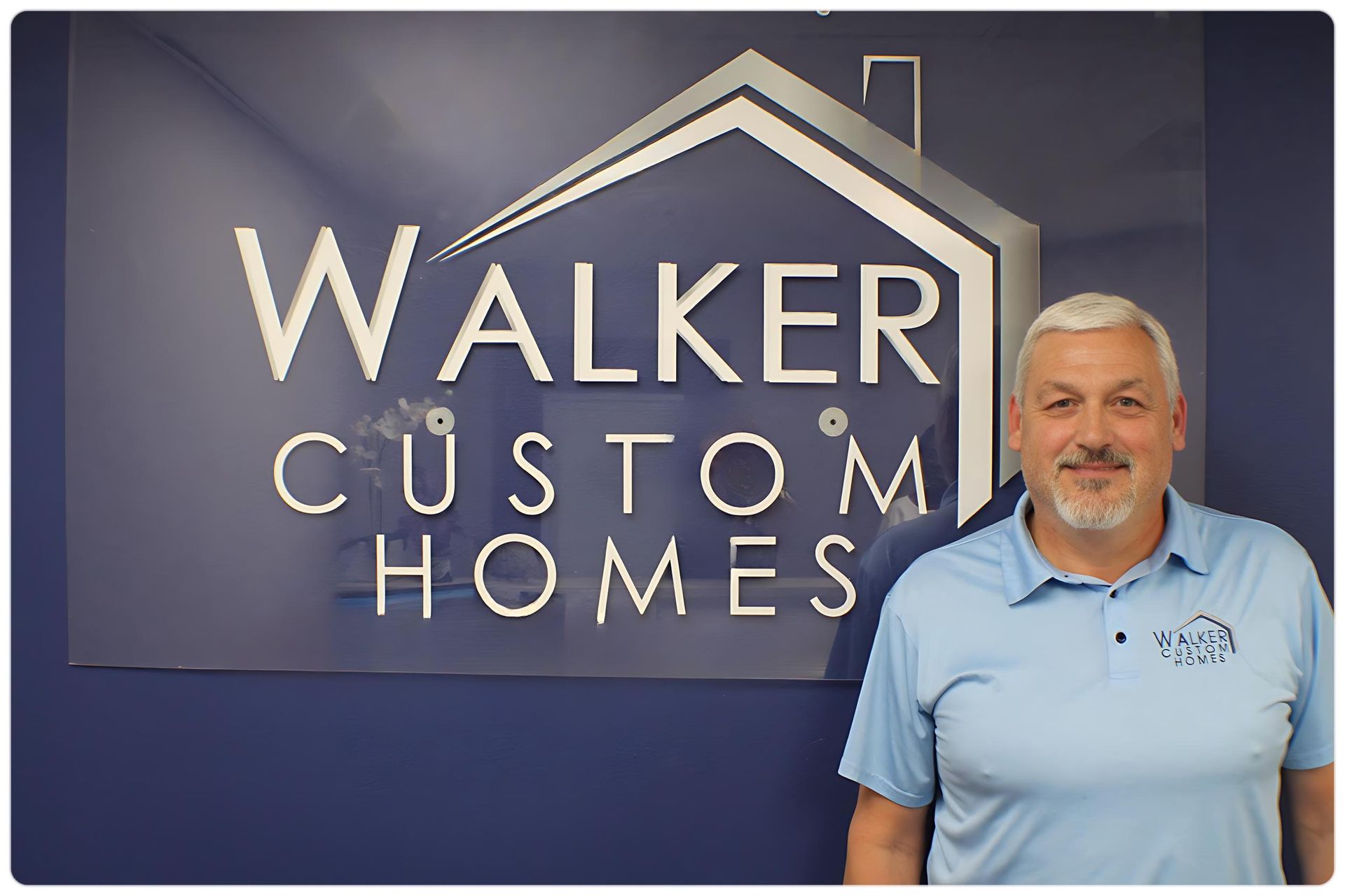 A man is standing in front of a walker custom homes sign.