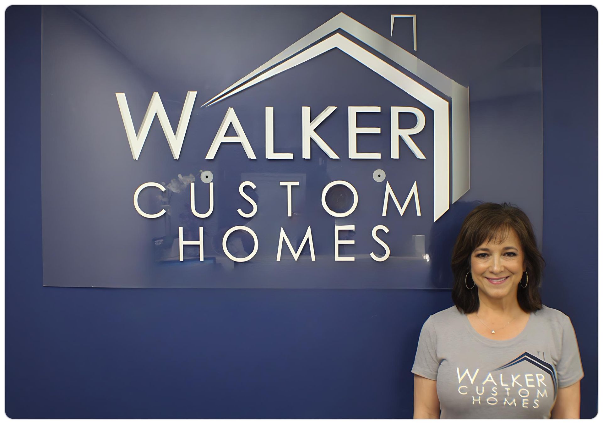 A woman is standing in front of a walker custom homes sign.