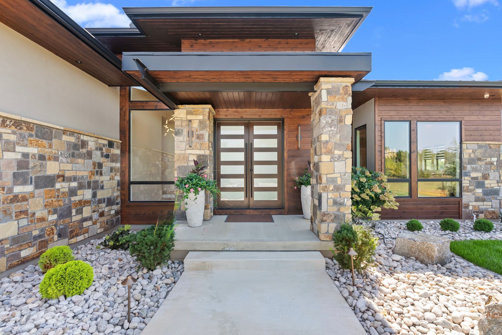 Modern home exterior with stone accents and wood front door.