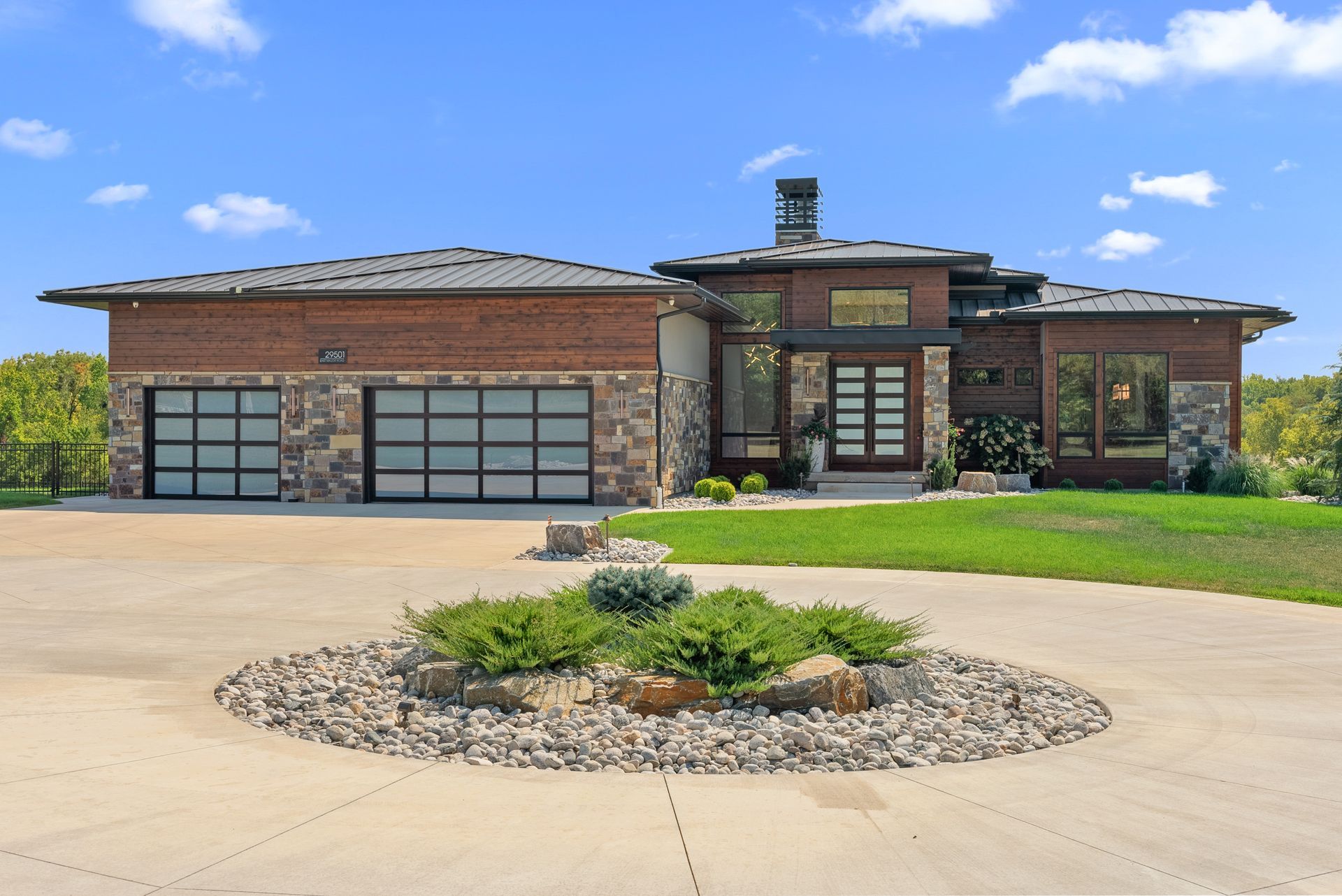Modern brick and stone house with circular driveway and landscaping.