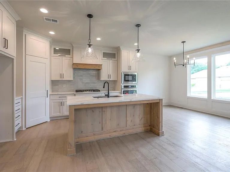 Modern kitchen with white cabinets, wood island, and light wood floors.