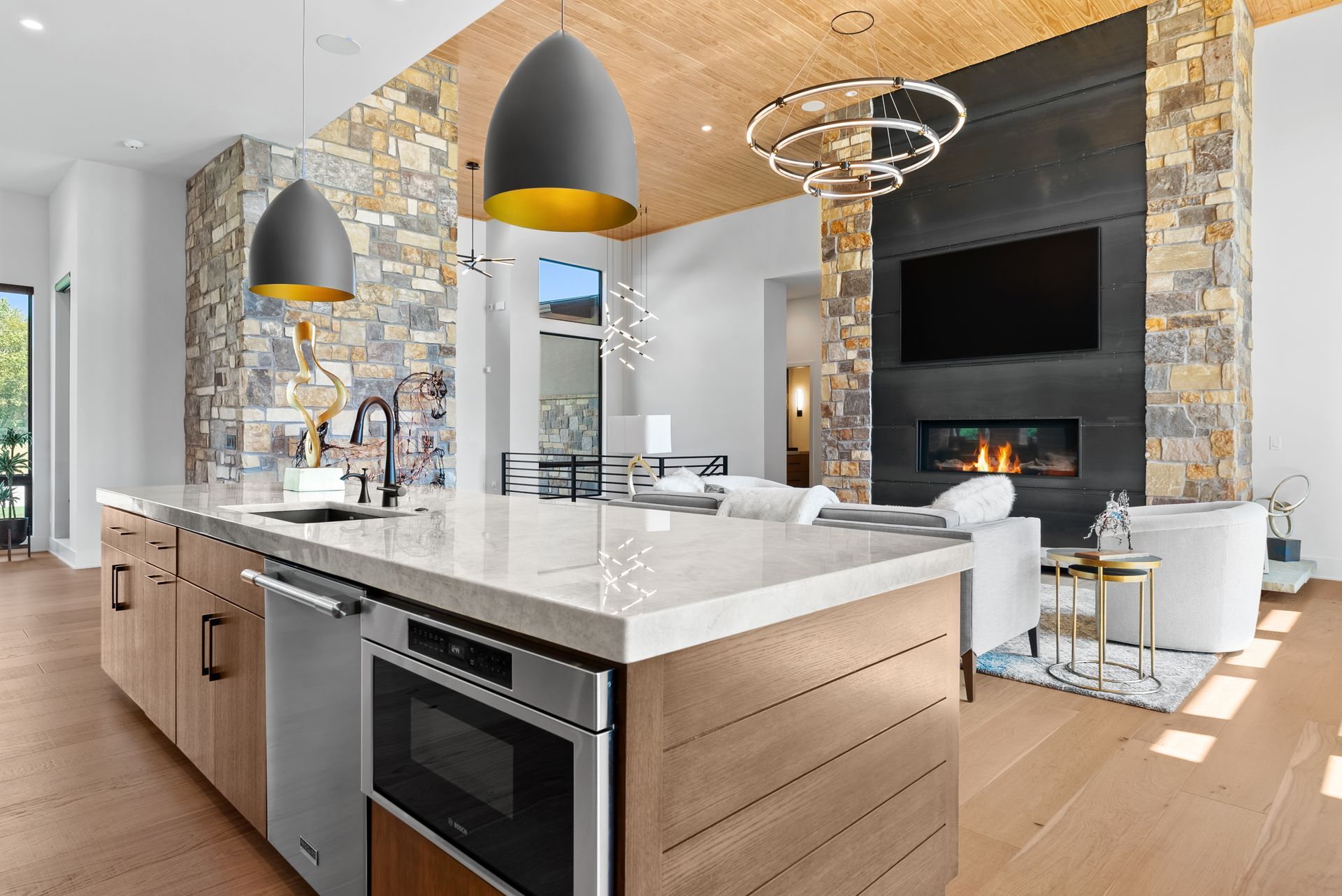 Modern kitchen with stone accent wall, island, and fireplace.
