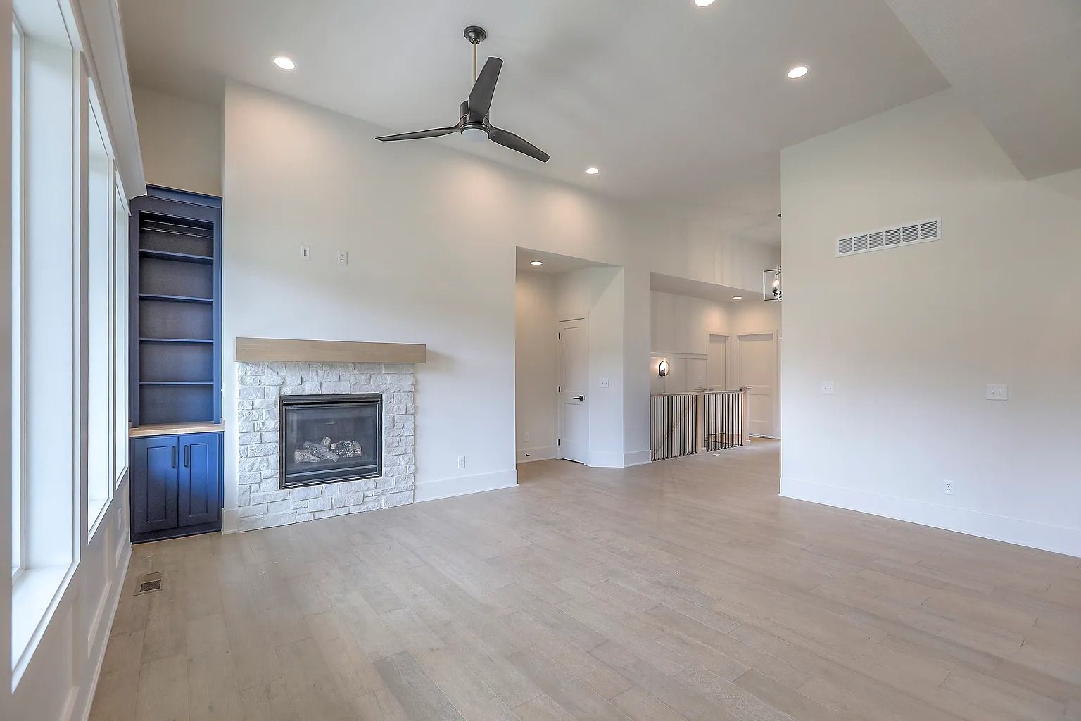 Empty living room with fireplace, built-in shelves, and hardwood floors.
