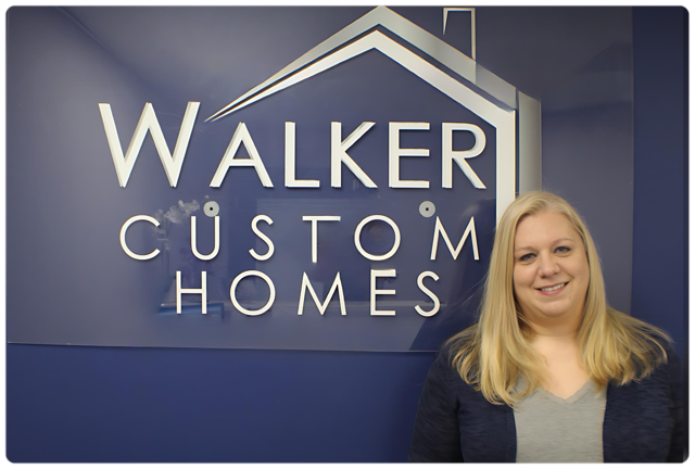 A woman stands in front of a walker custom homes sign