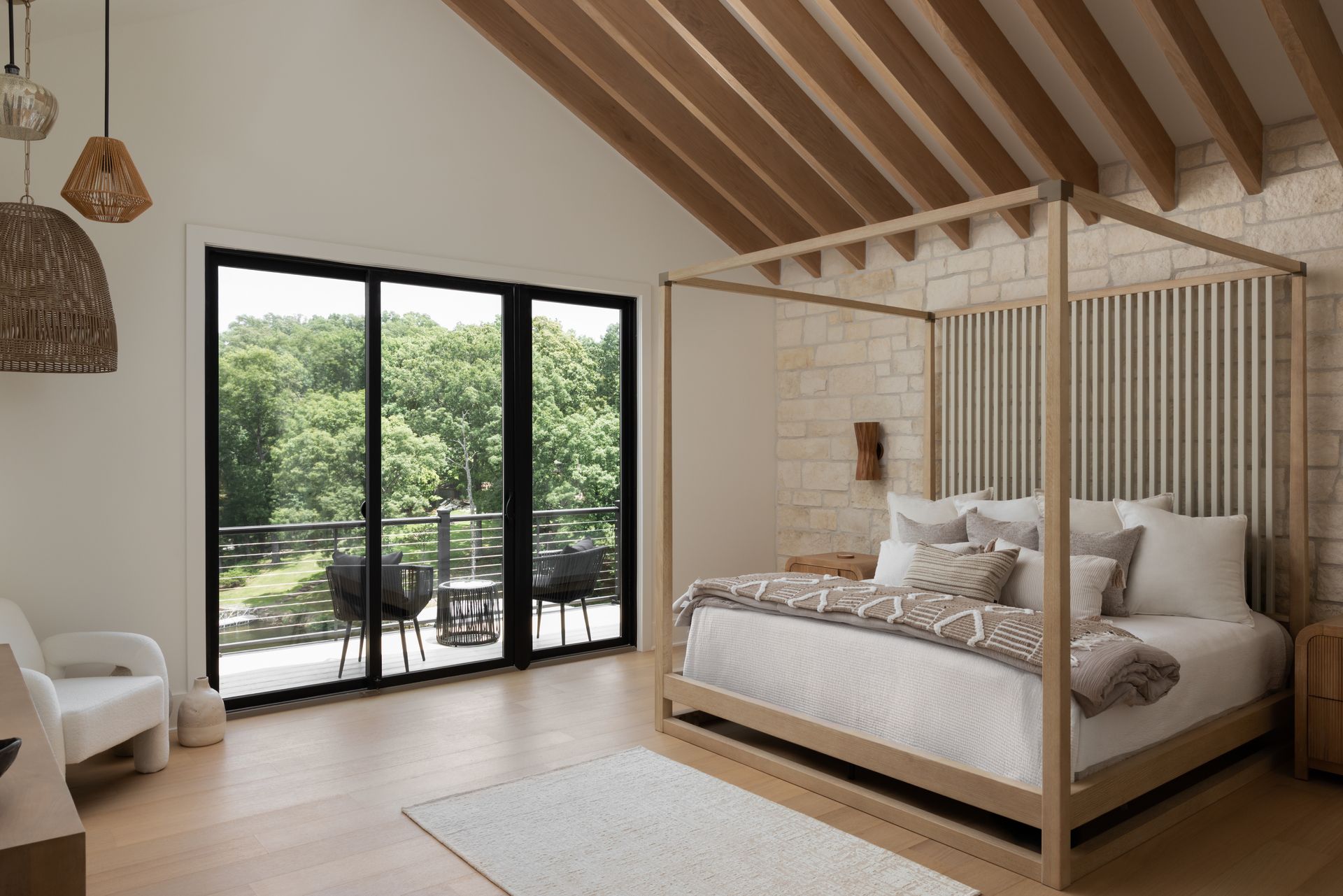 Bedroom with four-poster bed, balcony, and wooden ceiling beams; light and airy feel.