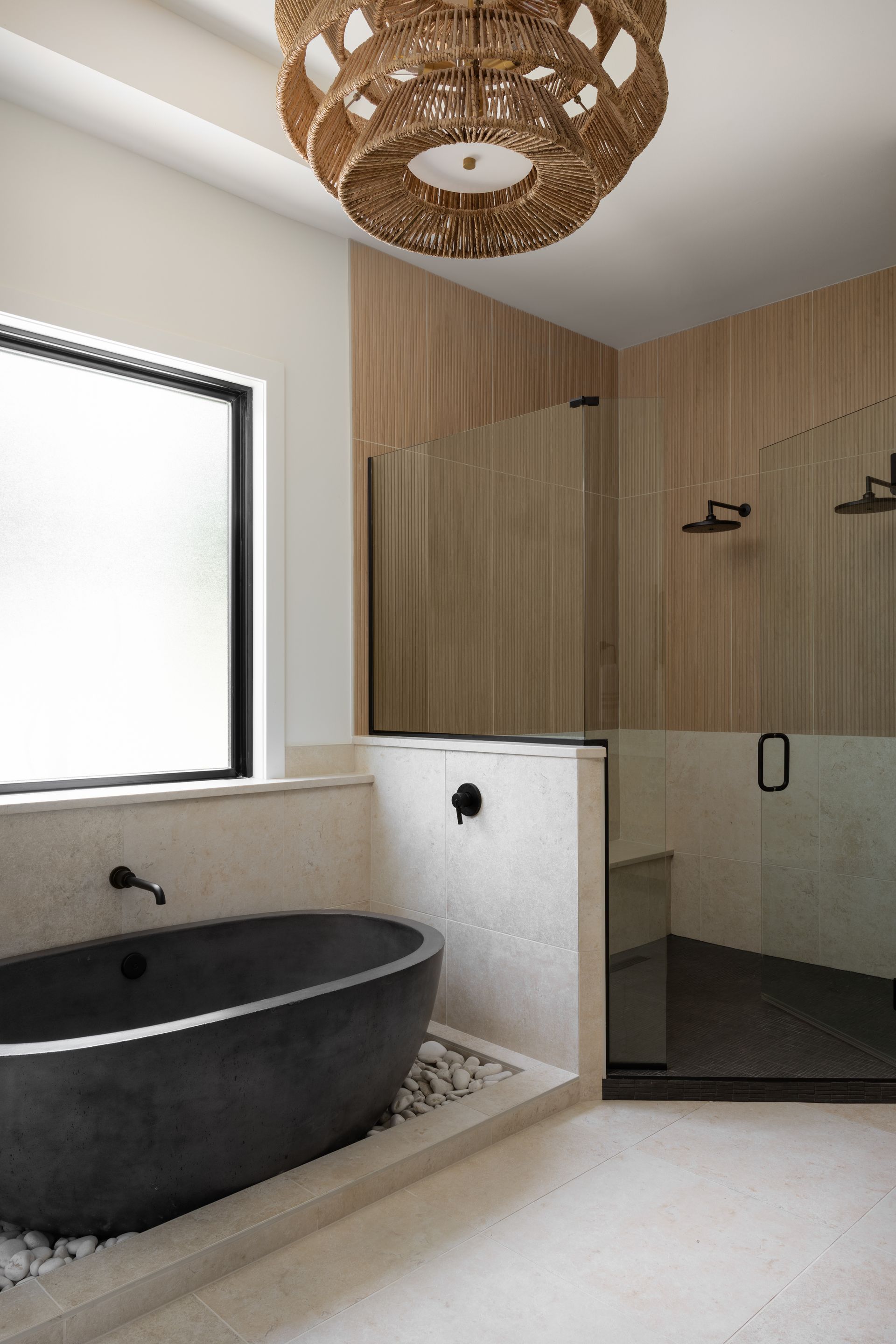 Modern bathroom with a dark oval tub, shower, and wood accents.