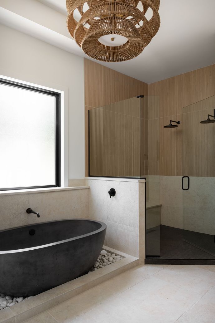 Modern bathroom with a dark oval tub, shower, and wood accents.