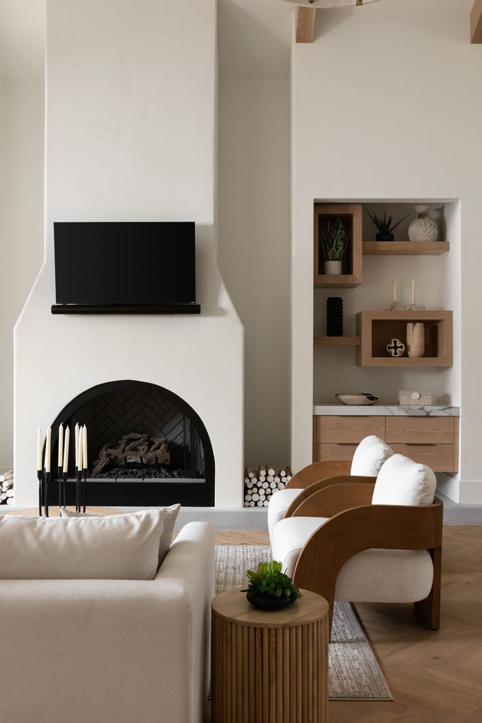 Living room with white fireplace, built-in shelving, wooden chairs, and a coffee table.