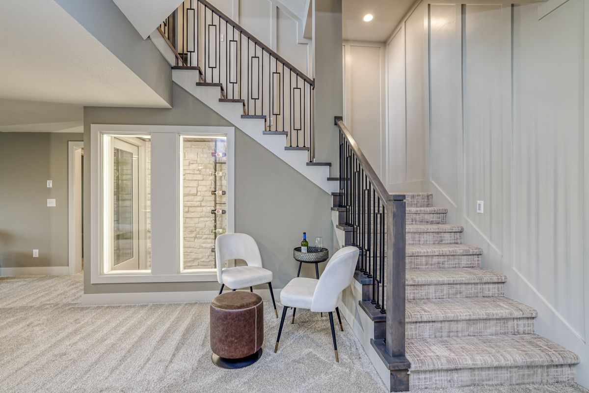 There is a staircase in the middle of the room with chairs and ottomans.