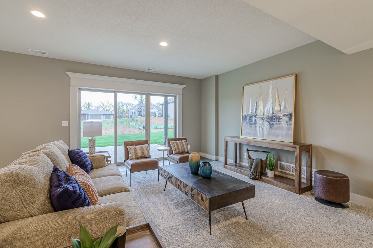 A living room with a couch , chairs , coffee table and sliding glass doors.