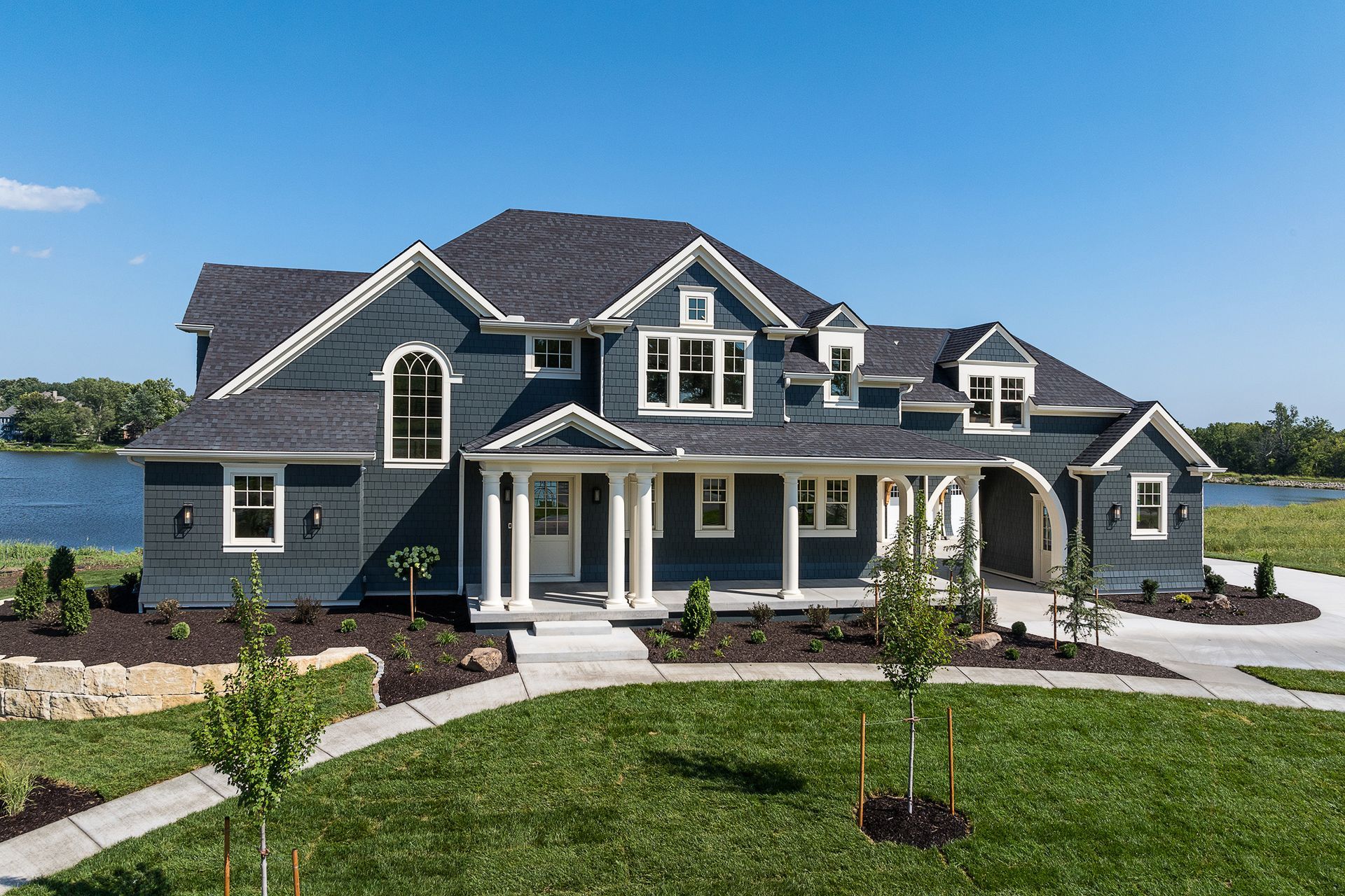 A large house with a lot of windows is sitting next to a lake.
