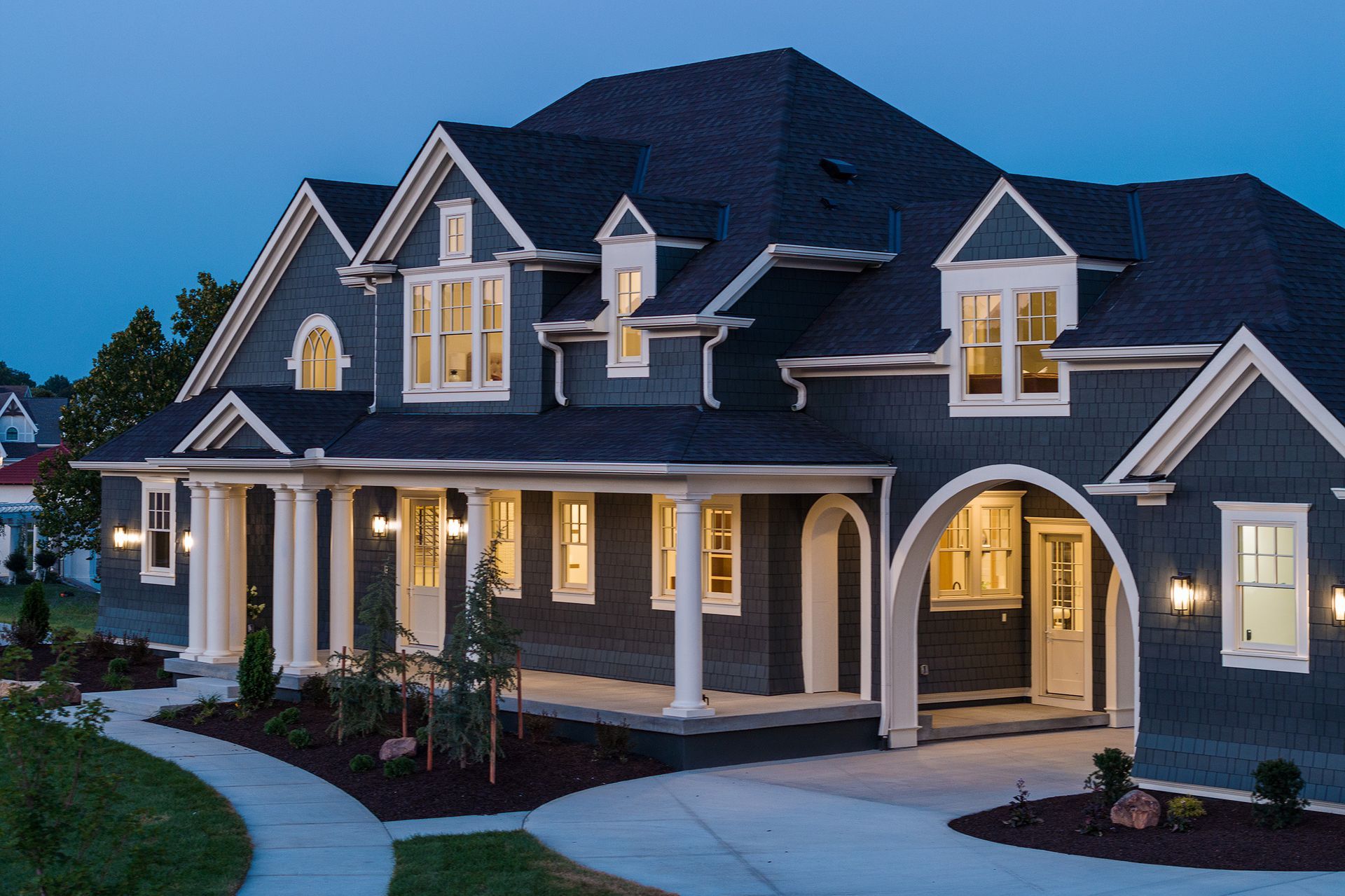 A large house with a large porch is lit up at night