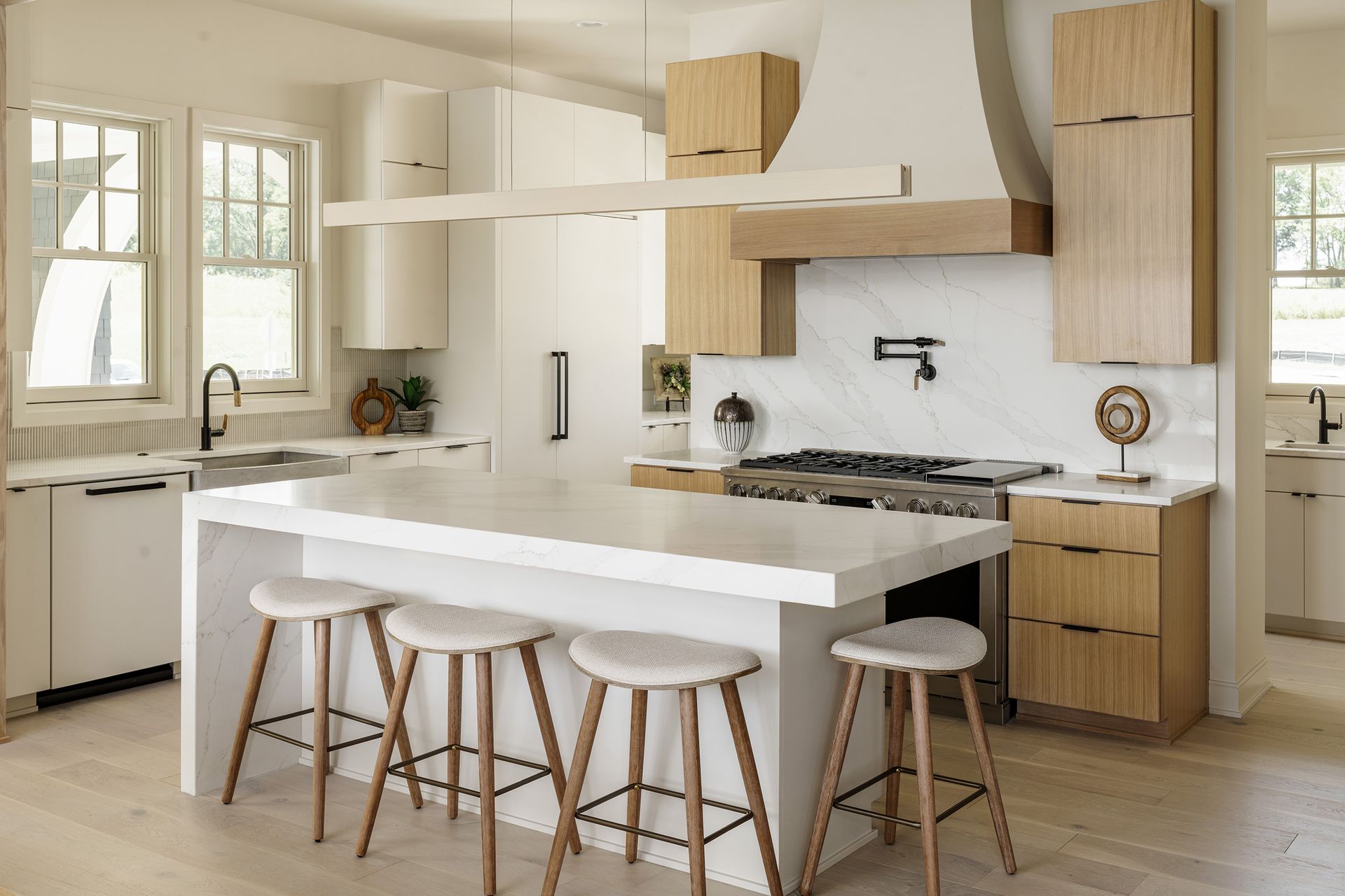A kitchen with white cabinets and wooden stools and a large island.
