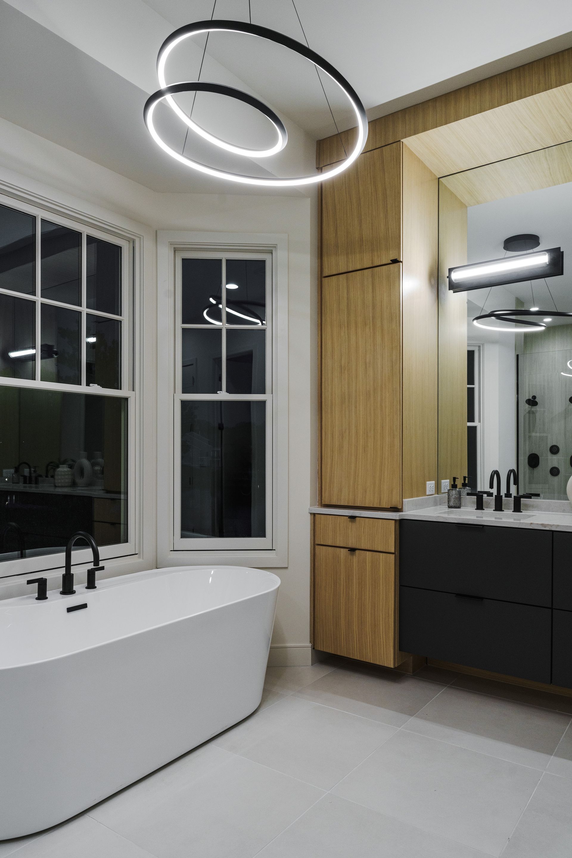 A bathroom with a tub , sink , mirror and window.