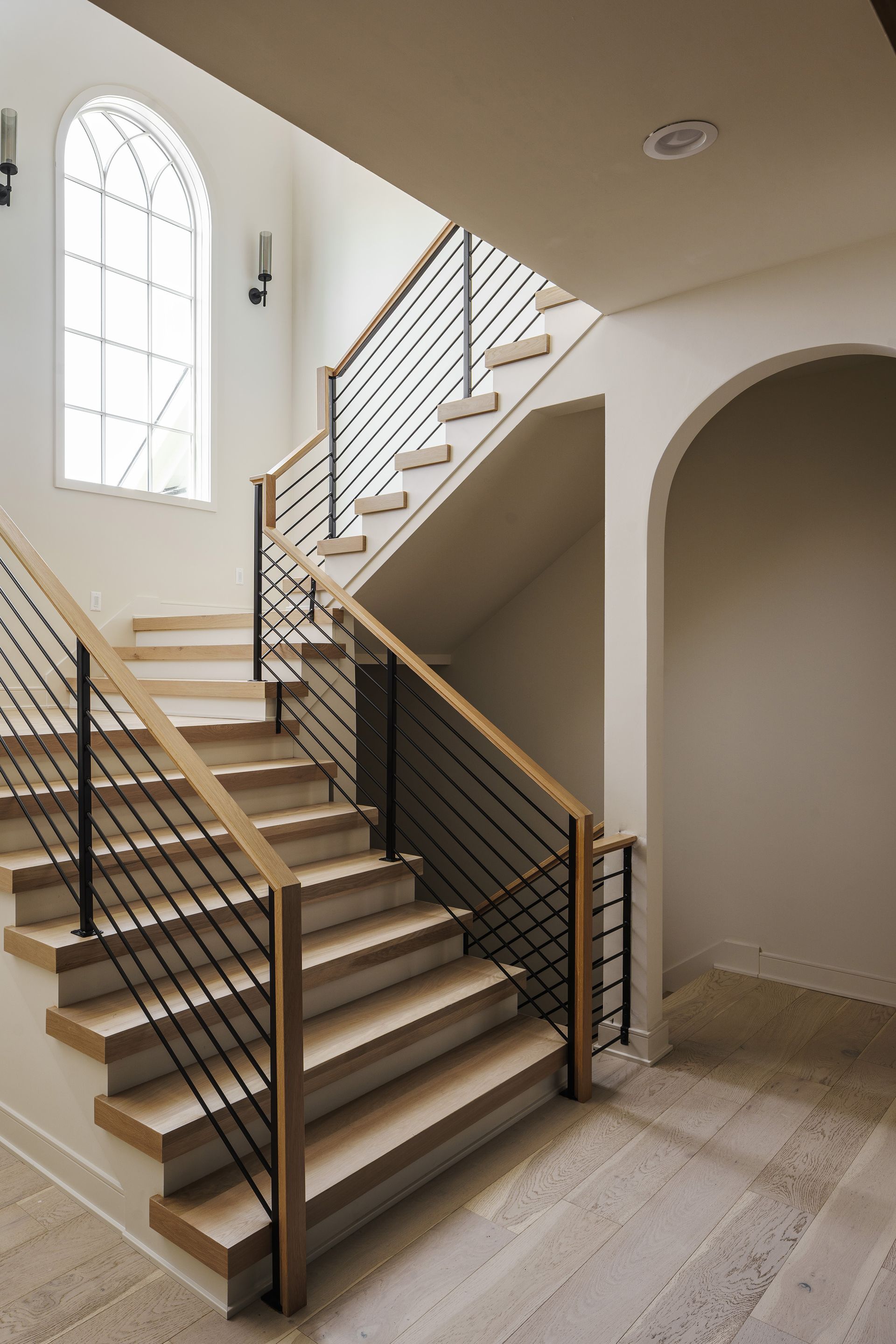 A staircase with a wooden railing and a window in the background.