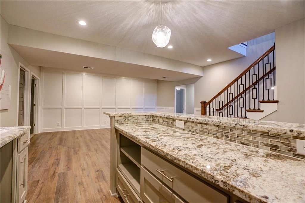A kitchen with granite counter tops and a staircase in the background.