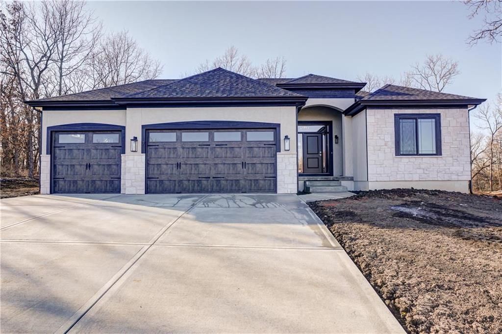 A large house with three garage doors and a concrete driveway.