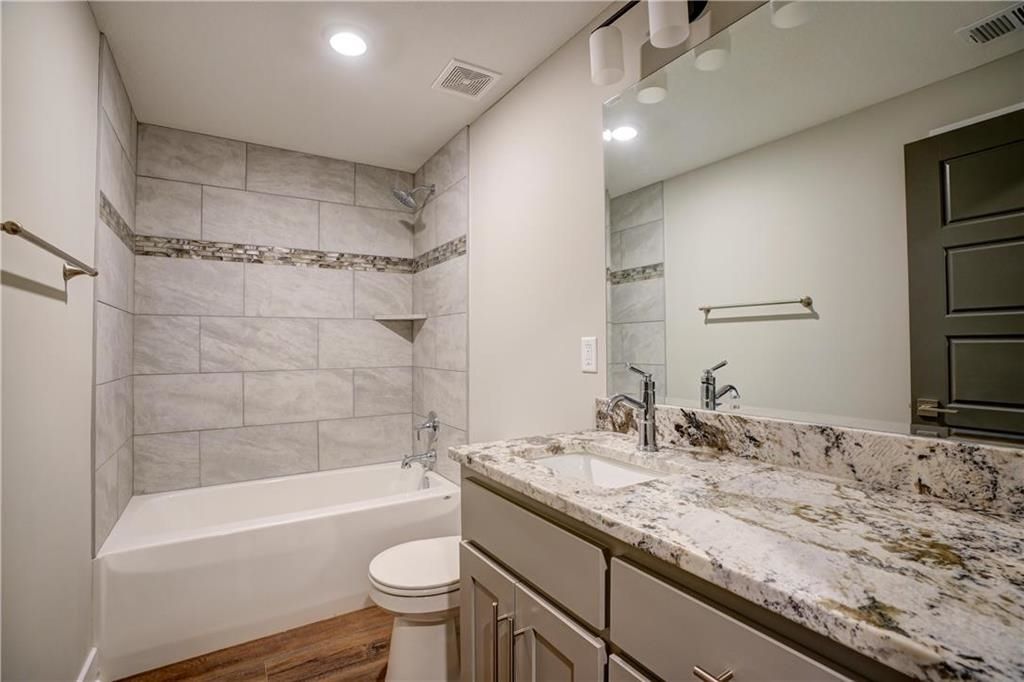 A bathroom with a tub , sink , toilet and mirror.