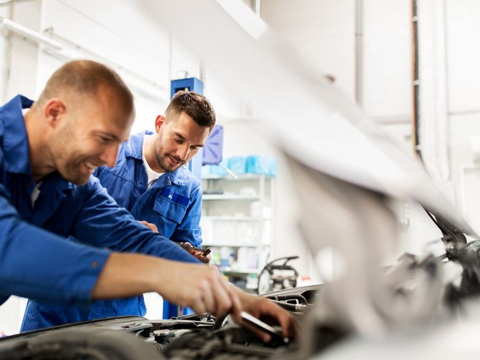 Two mechanics in uniform working at auto