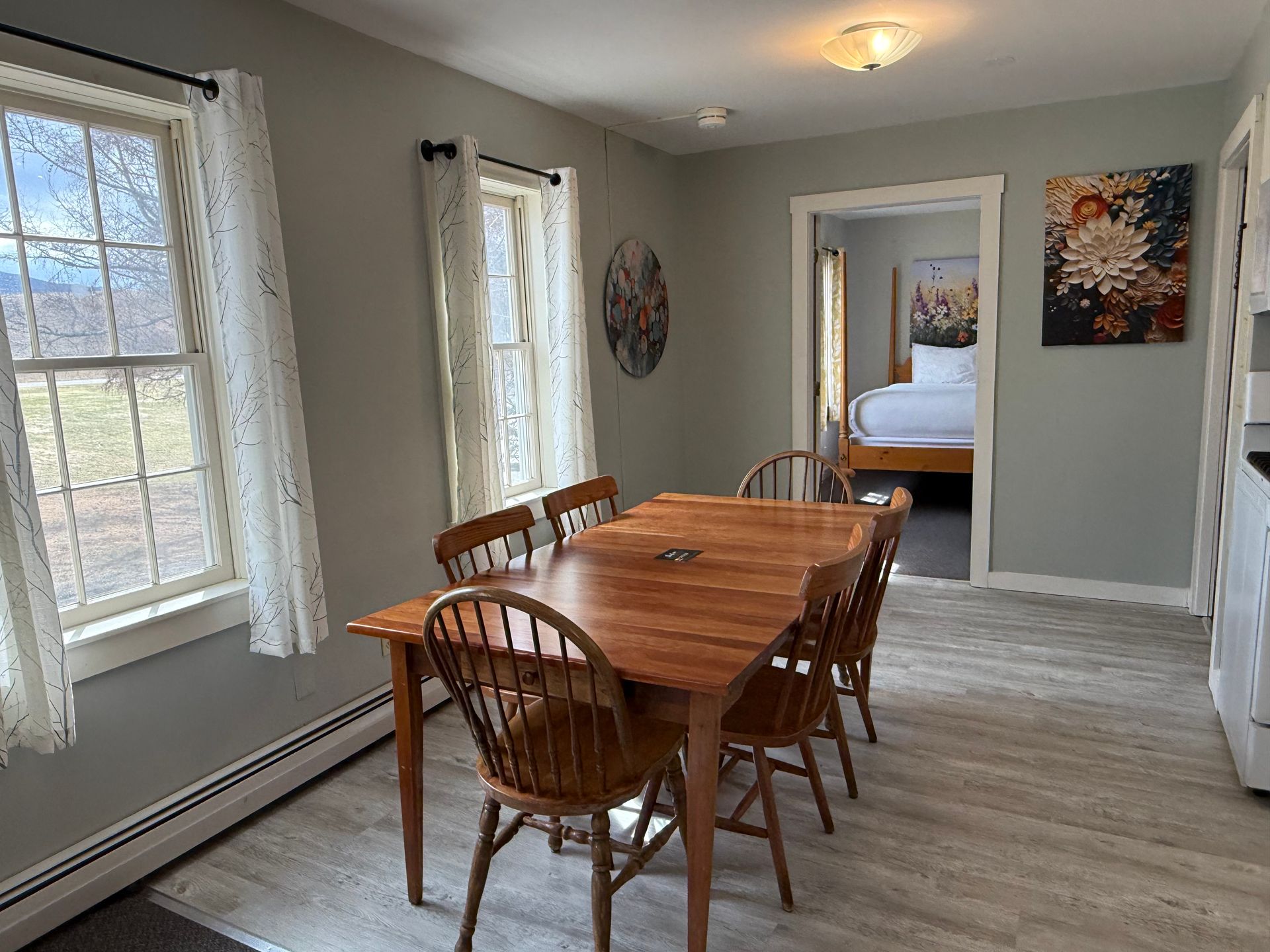 Dining room with wooden table and chairs, gray walls, and an open doorway to a bedroom.