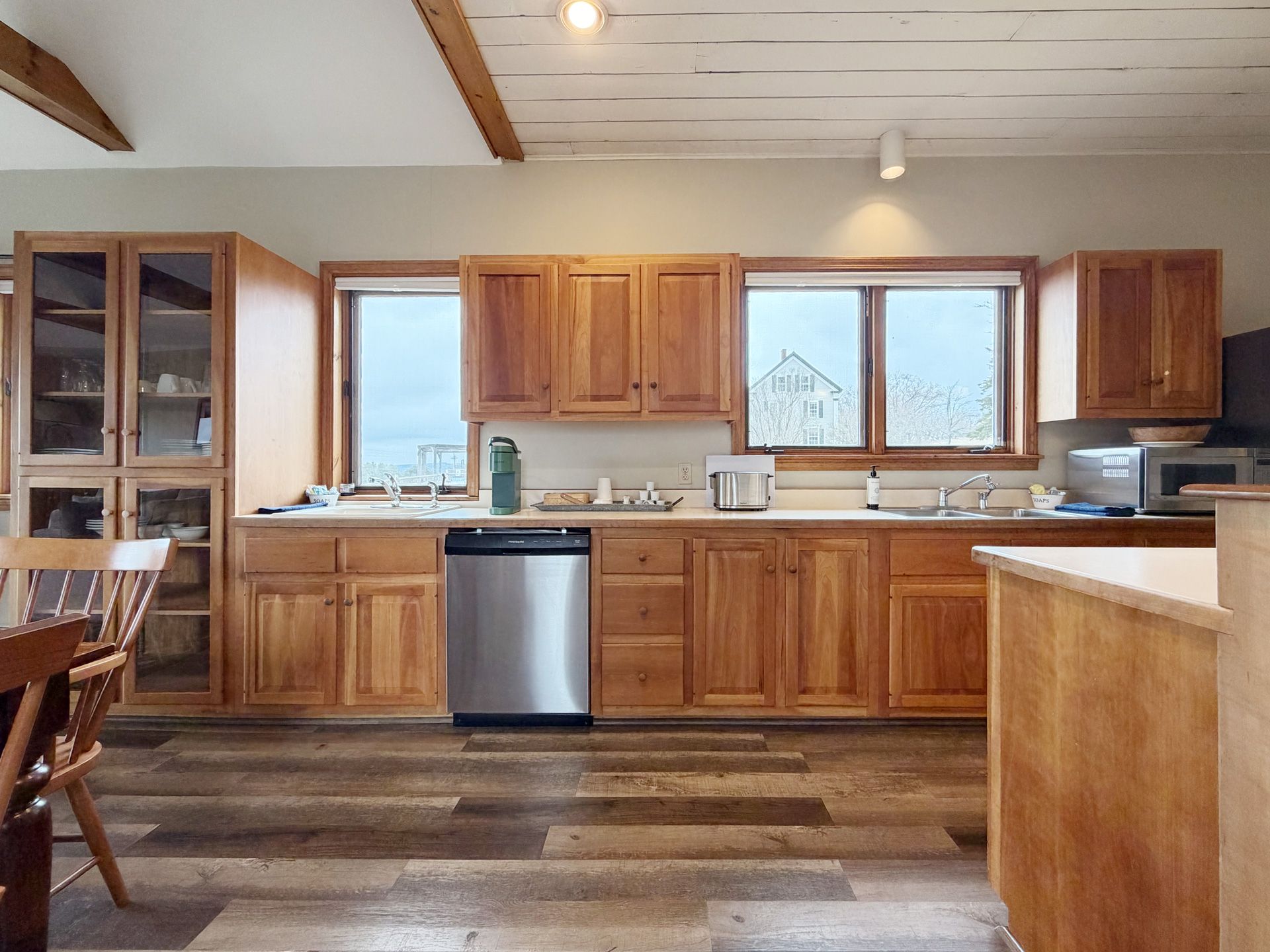 Wooden kitchen with cabinets, large windows, stainless dishwasher, and a hardwood floor