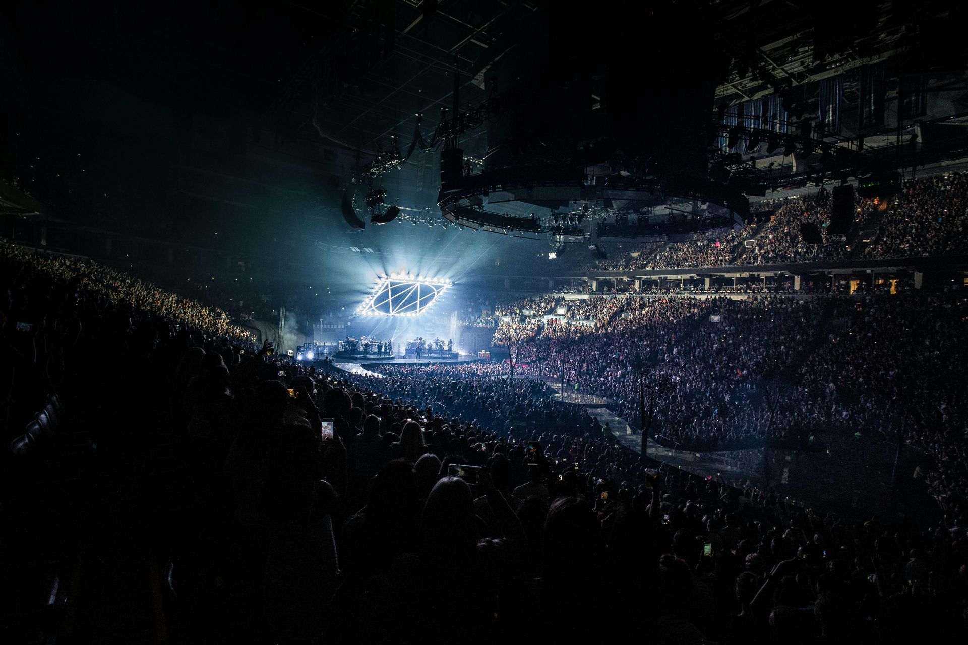 A crowd of people are watching a concert in a stadium at night.