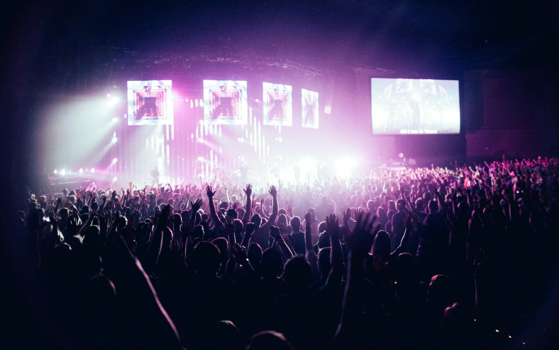 A crowd of people are standing in front of a stage at a concert.