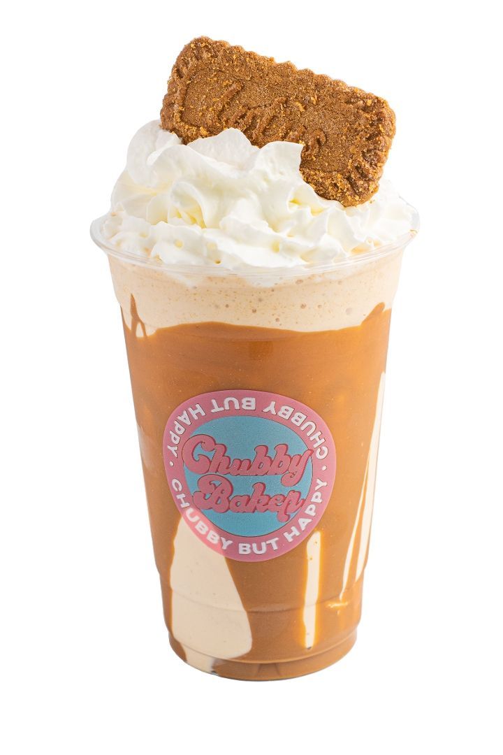 A large milkshake in a clear cup with whipped cream and a cookie on top. The drink is brown and has a logo.