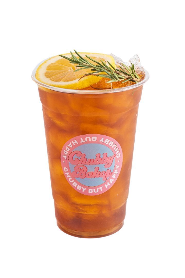 Iced tea with orange slice and rosemary garnish in a clear plastic cup.