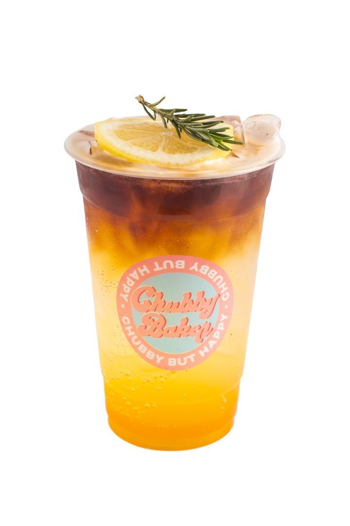 Iced drink with layered colors, topped with a lemon slice and rosemary sprig, in a clear cup with logo label.