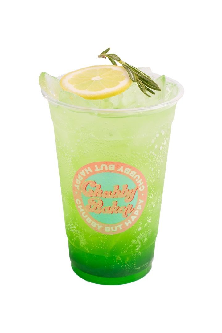 Green drink in a clear plastic cup, garnished with lemon and rosemary.