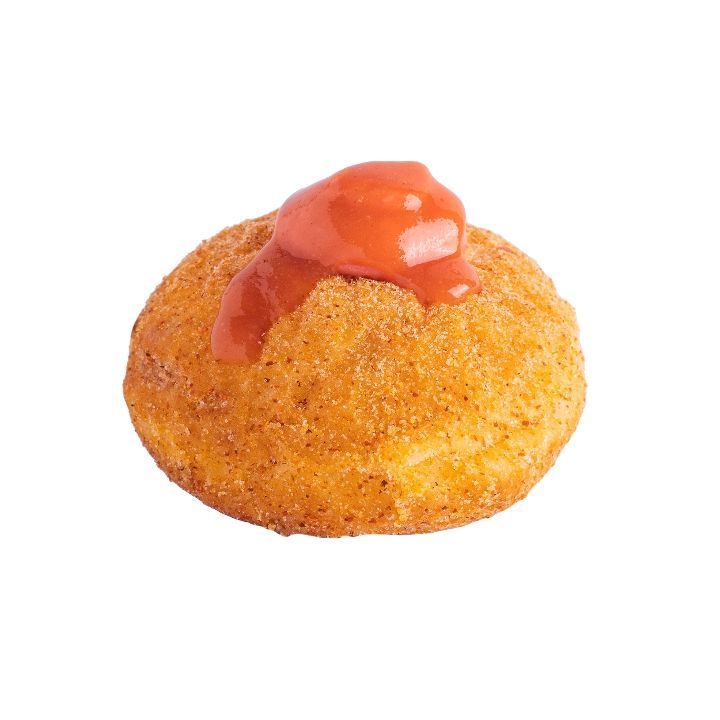 A deep-fried arancini ball, topped with a dollop of red sauce.