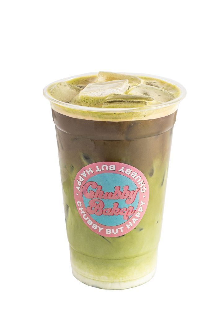 Iced matcha latte in a clear cup, layered with green matcha, milk, and a top layer of matcha. Features a pink sticker on the cup.
