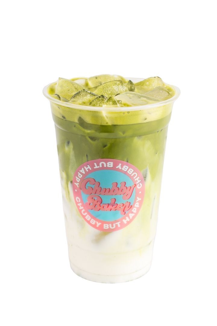Iced matcha latte in a clear cup with a logo. Layers of white milk, green matcha, and ice.