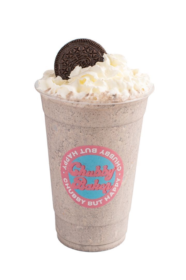 Oreo milkshake in a clear cup topped with whipped cream and a cookie. The cup has the logo 