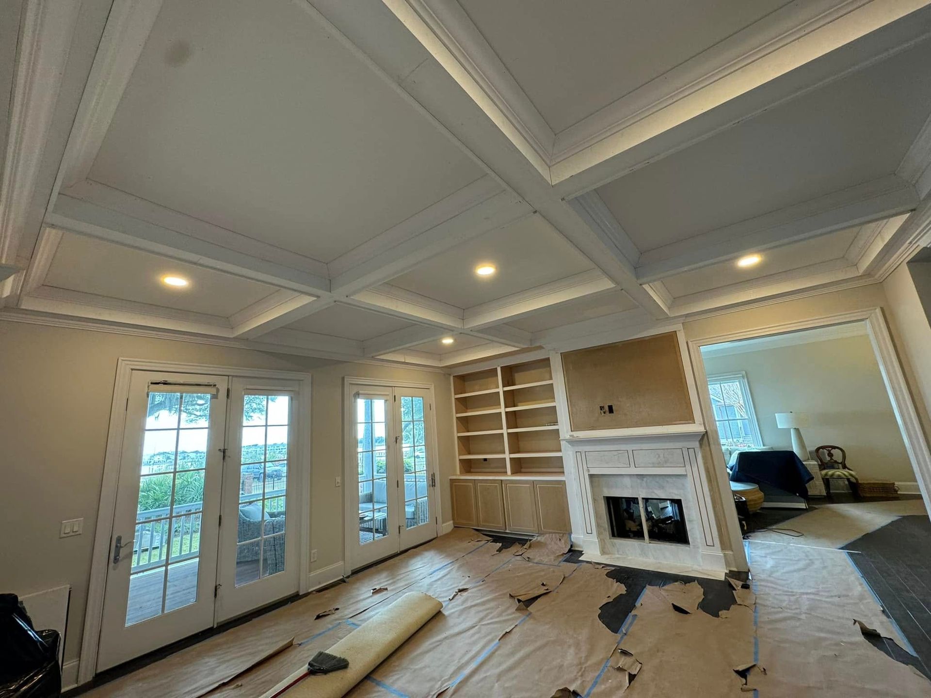 Interior room with coffered ceiling, recessed lights, French doors, built-in bookshelves, and fireplace.