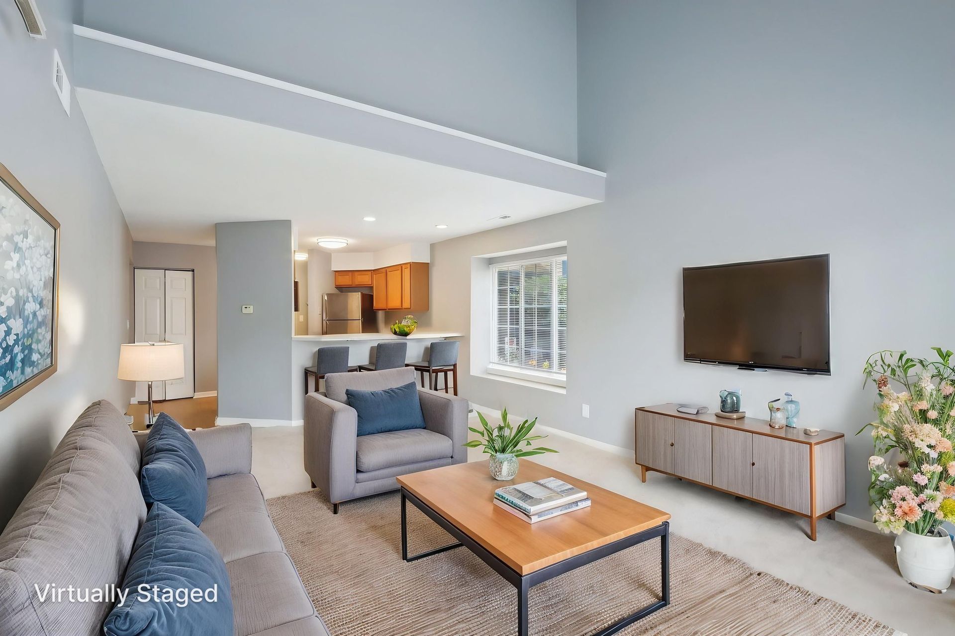Living room with sofa, chair, TV, and open kitchen; neutral colors.