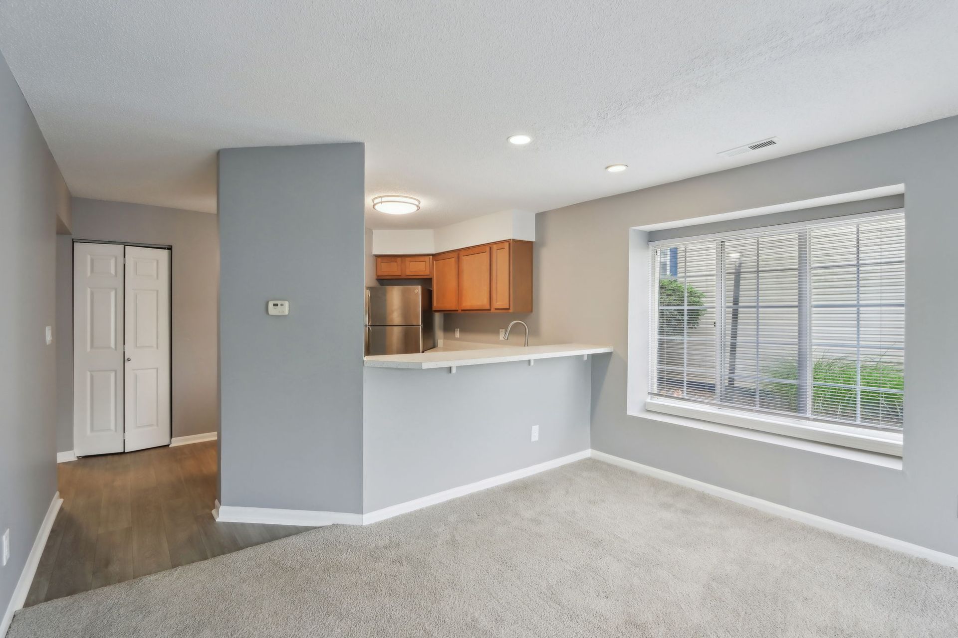 Cozy apartment interior with open kitchen, gray walls, and carpet.