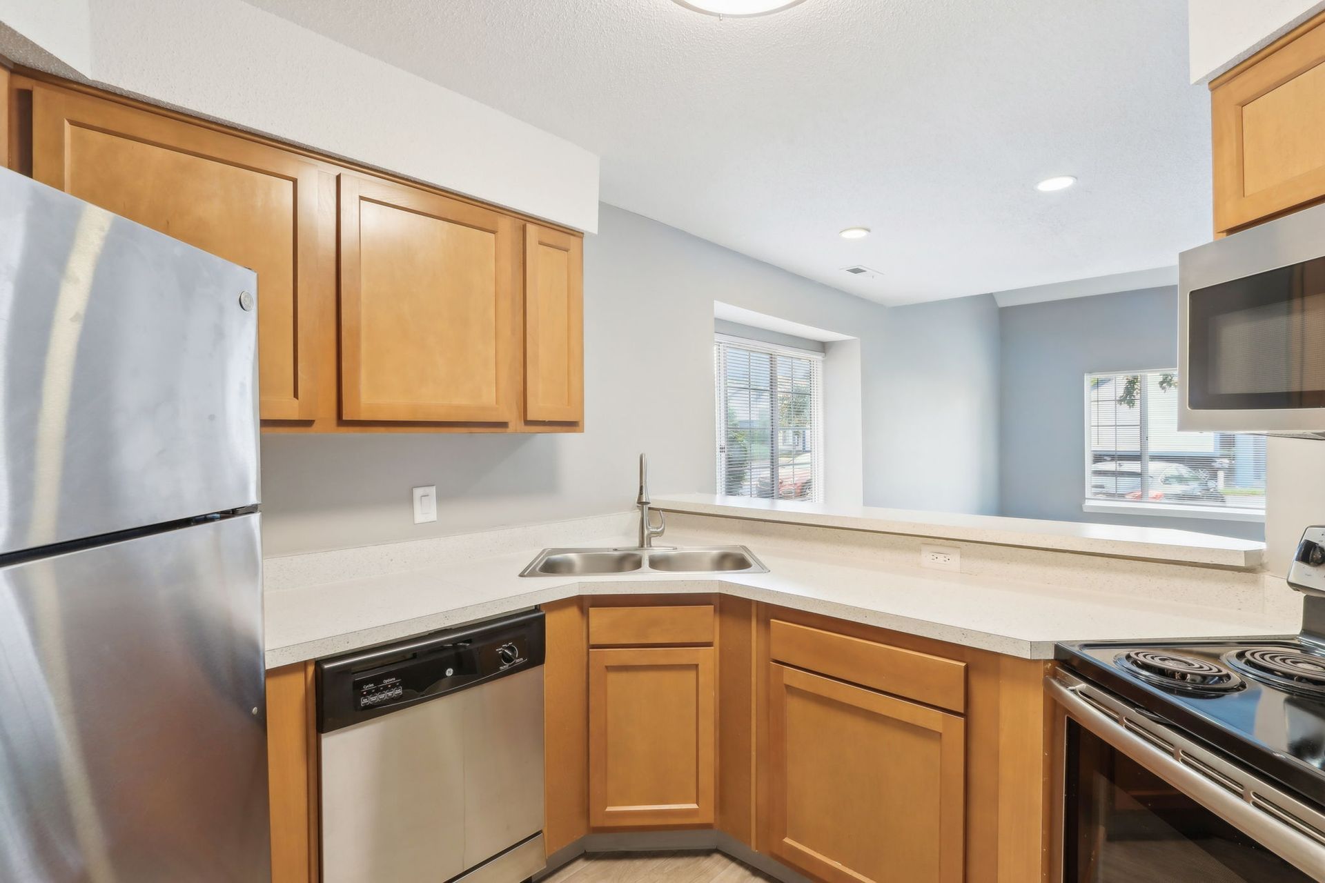 Kitchen with light wood cabinets, stainless steel appliances, and a breakfast bar.