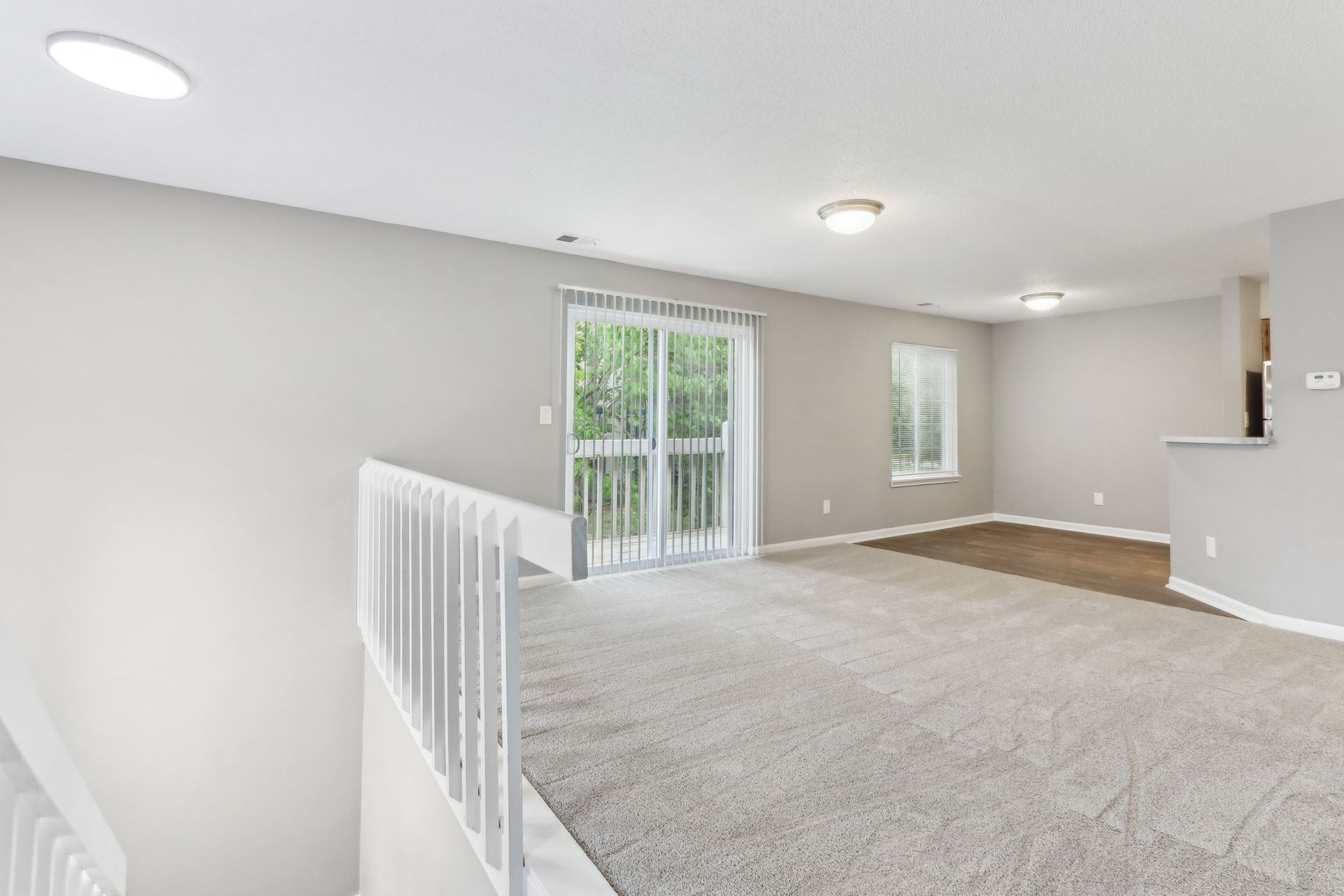Loft with carpet, sliding glass door to a balcony, light gray walls, and white railing.