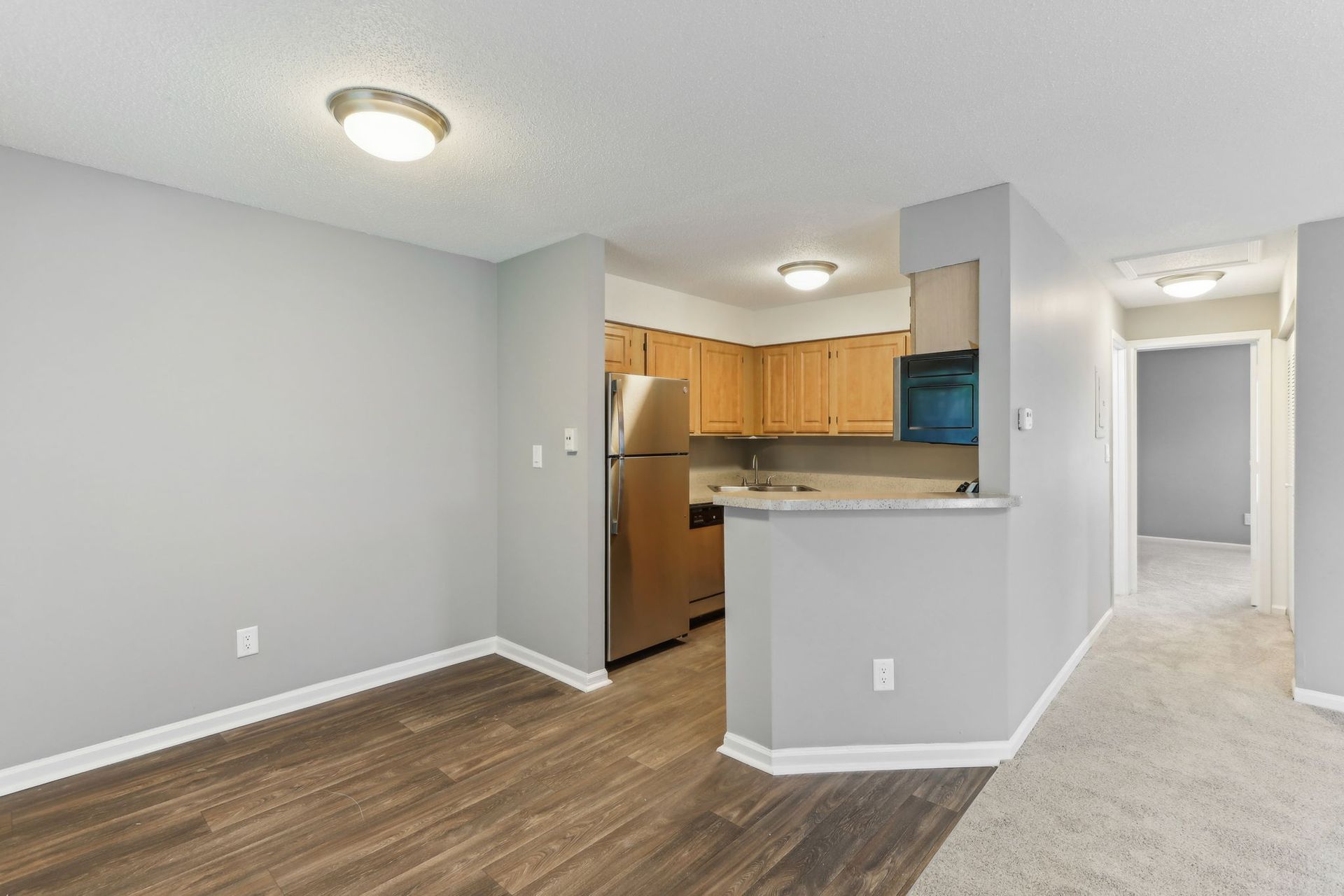 Interior view of an apartment with a dining area, kitchen with stainless steel appliances, and hallway.