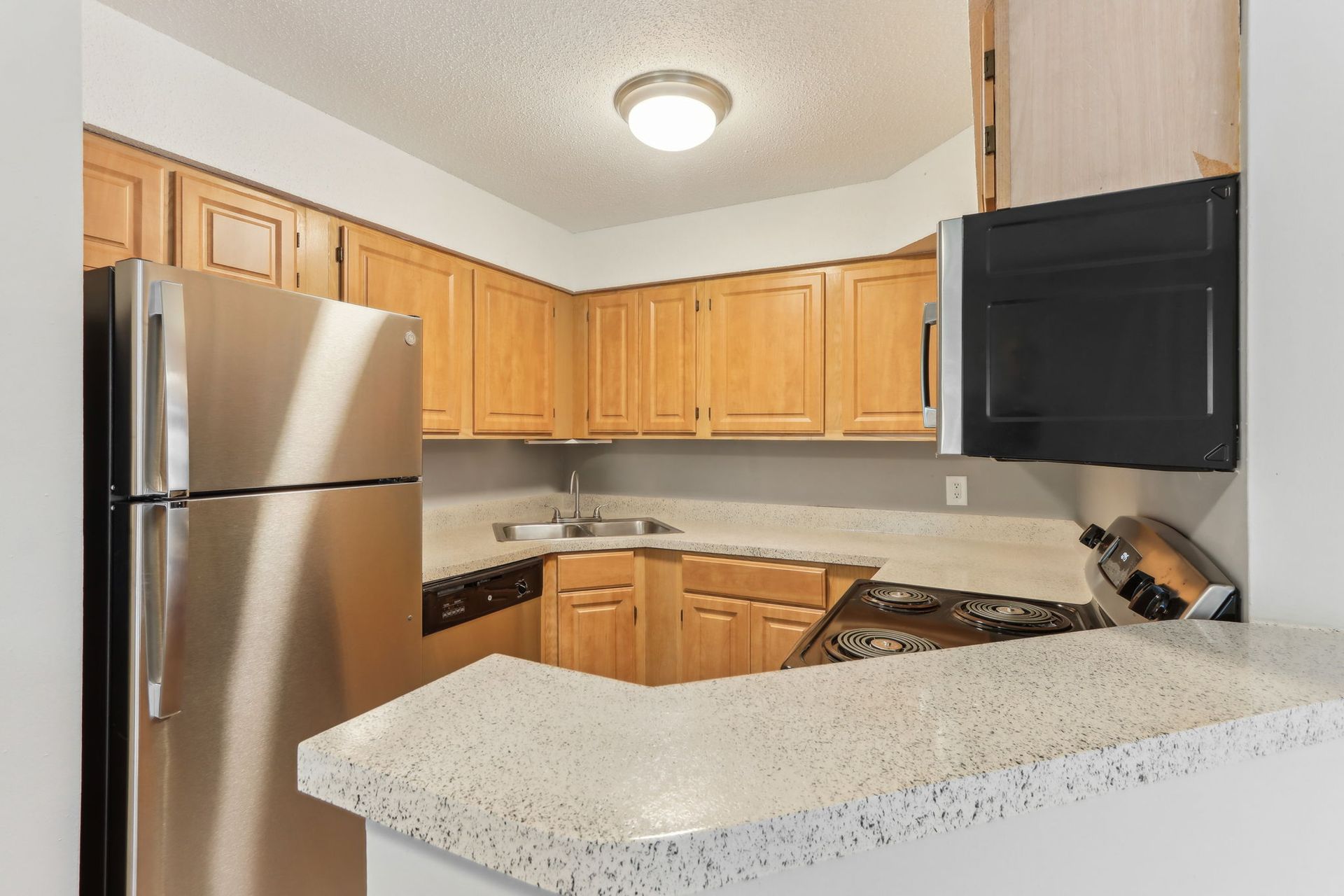 Kitchen with light wood cabinets, stainless steel refrigerator, and countertop.