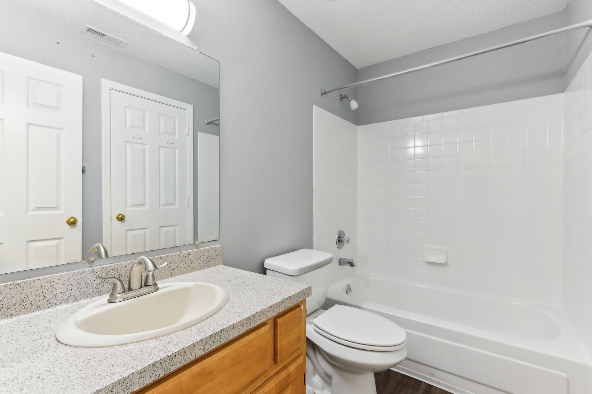 Bathroom with white fixtures, gray walls, and a wooden vanity.