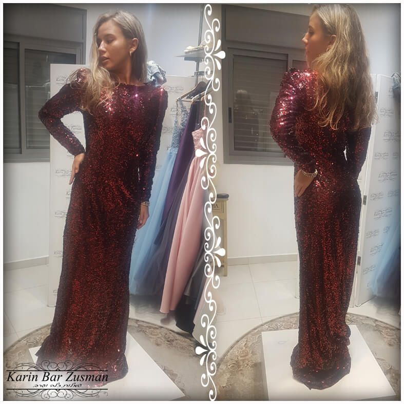 אישה בשמלת בורדו מנצנצים, מבט ממראה באורך מלא. שרוולים ארוכים, עומדת בתוך הבית מול רקע של חנות.