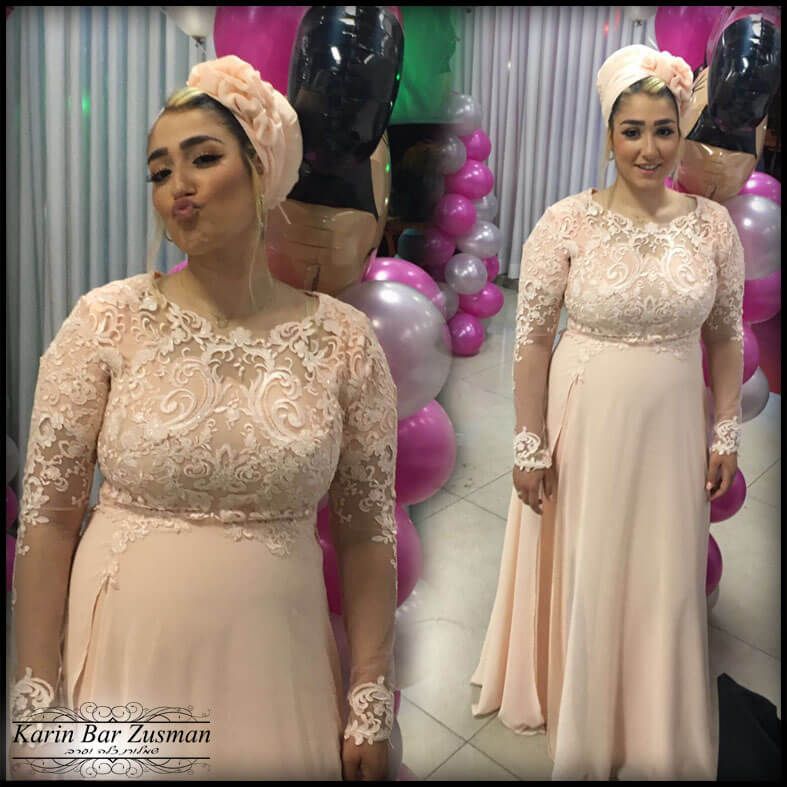 אישה בשמלת תחרה בצבע אפרסק וטורבן, מצטלמת עם בלונים.