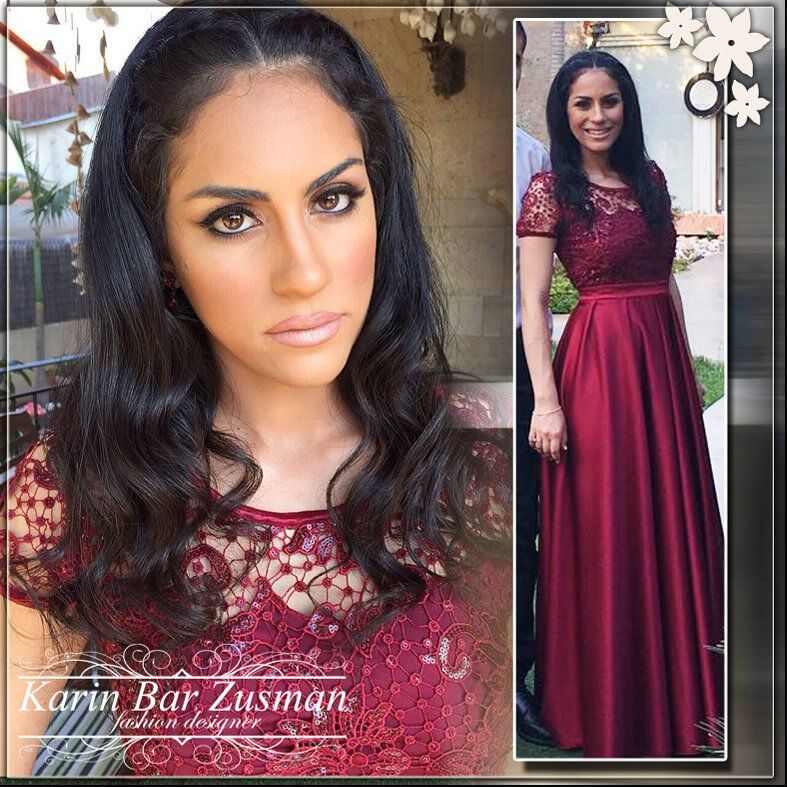 אישה בשמלת תחרה בצבע בורדו, שיער כהה ארוך והבעת פנים שלווה.