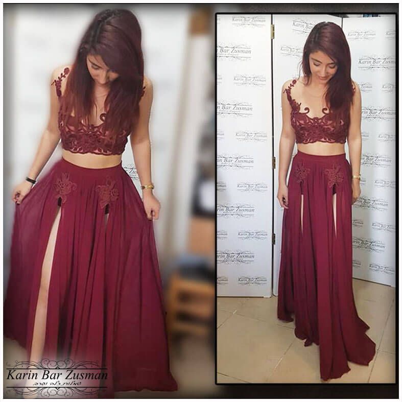 אישה בחולצה בגופיה חומה-אדמדמה וחצאית עם שסעים גבוהים, עומדת מול דלת.