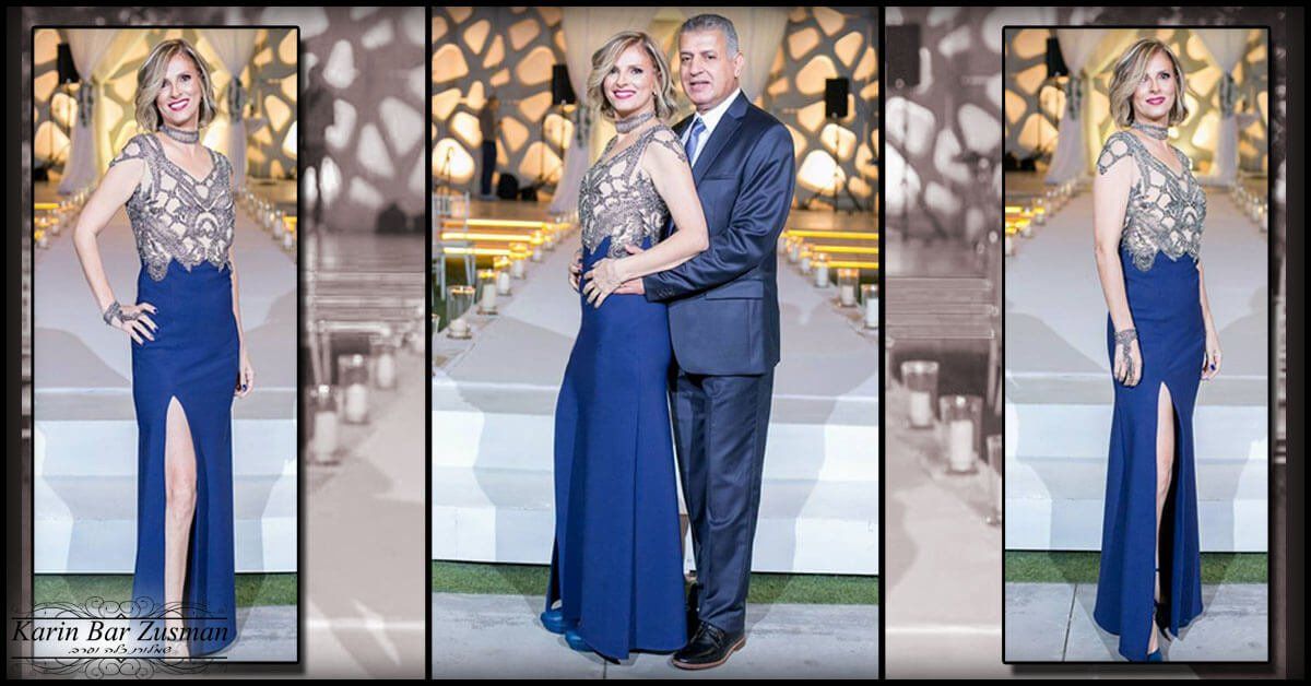 אישה בשמלה כחולה עם שס מצטלמת עם גבר. הם באווירה רשמית.