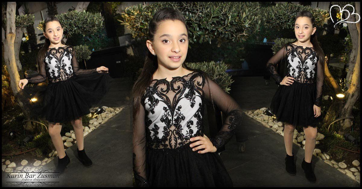 ילדה בשמלה שחורה מצטלמת בגן.